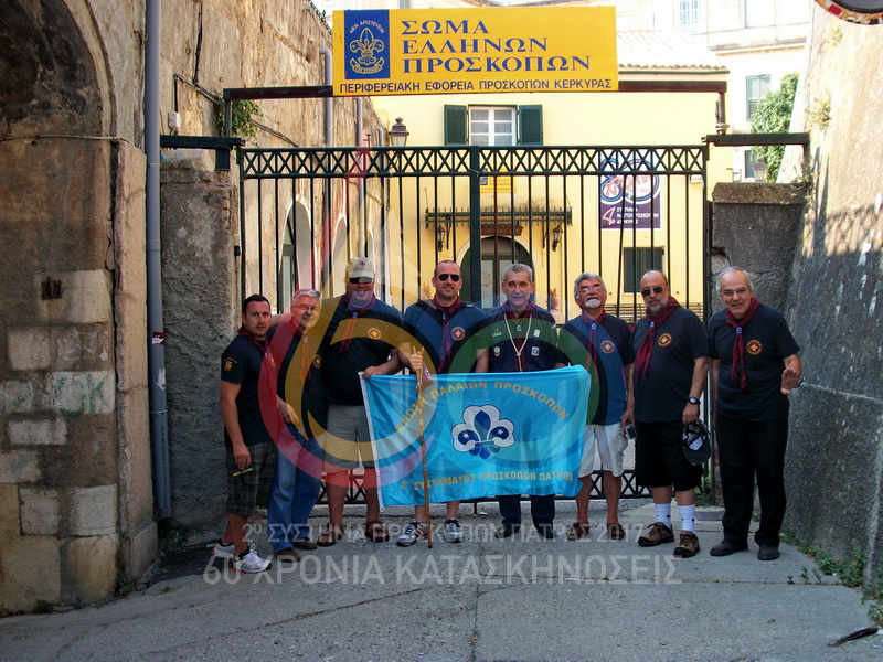 2013, 56η Κατασκήνωση της Ένωσης Παλαιών Προσκόπων 2ου Συστήματος Πάτρας στην Κέρκυρα. Οικογενειακή φωτογραφία στην πύλη του Προσκοπείου στο Φαληράκι.